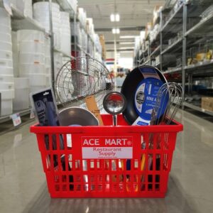 Red shopping basket full of cooking utensils.