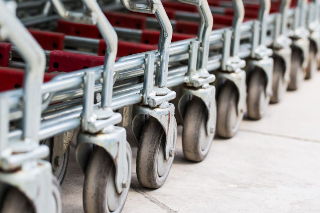 Shopping cart wheels with gray tires on concrete.