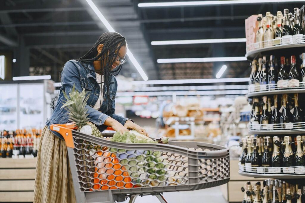 A woman with glasses and denim jacket shopping for groceries.