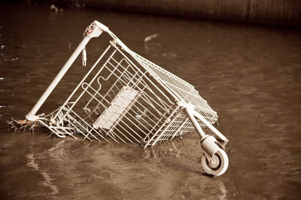 A shopping cart submerged in murky water.