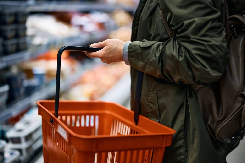 A red hand held basket being used in a retail store