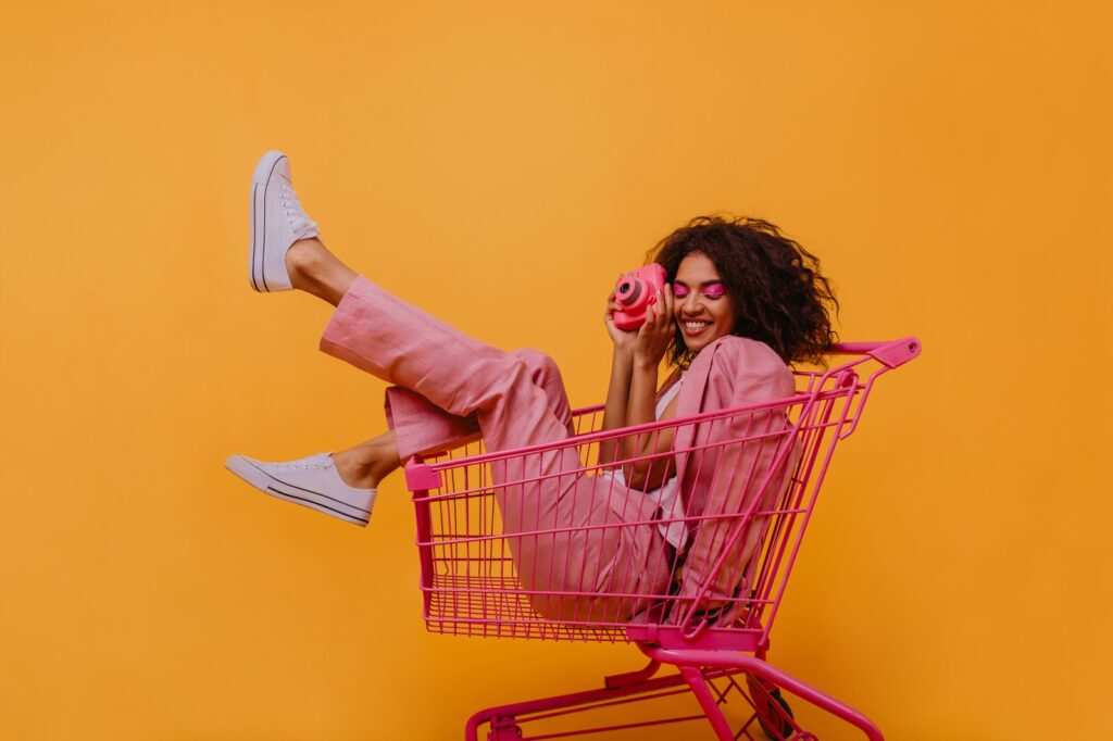 Woman sitting in a pink shopping cart