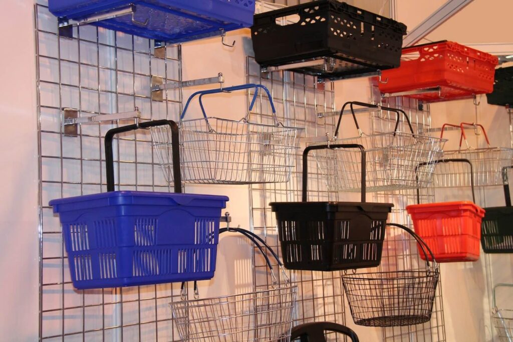 Colorful shopping baskets hanging on a wire grid.