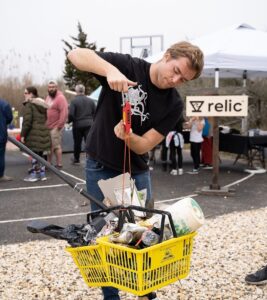 Man using a yellow shopping basket to pick up trash.