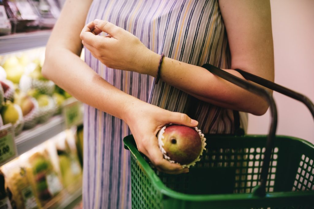 Shopper placing fruit in a shopping basket